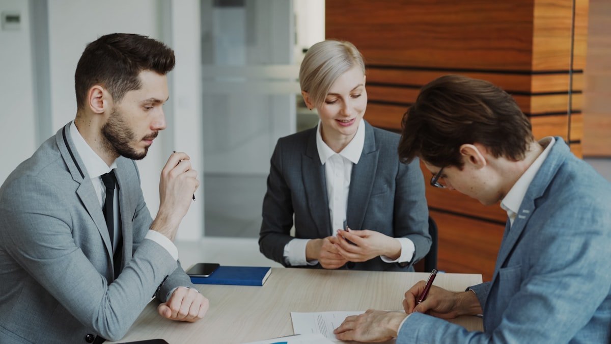 Abogado revisando documentos con su equipo alrededor de una mesa de trabajo